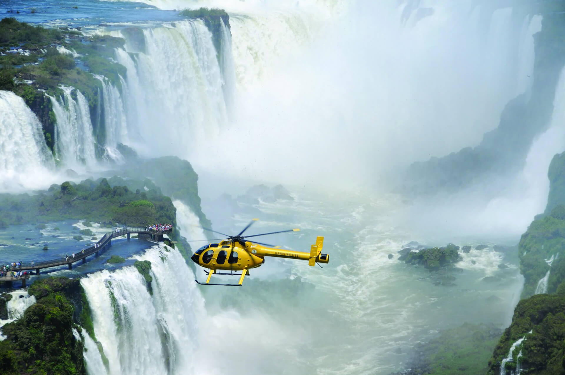 Private helicopter hovers Iguazu Falls and mist during luxury tour