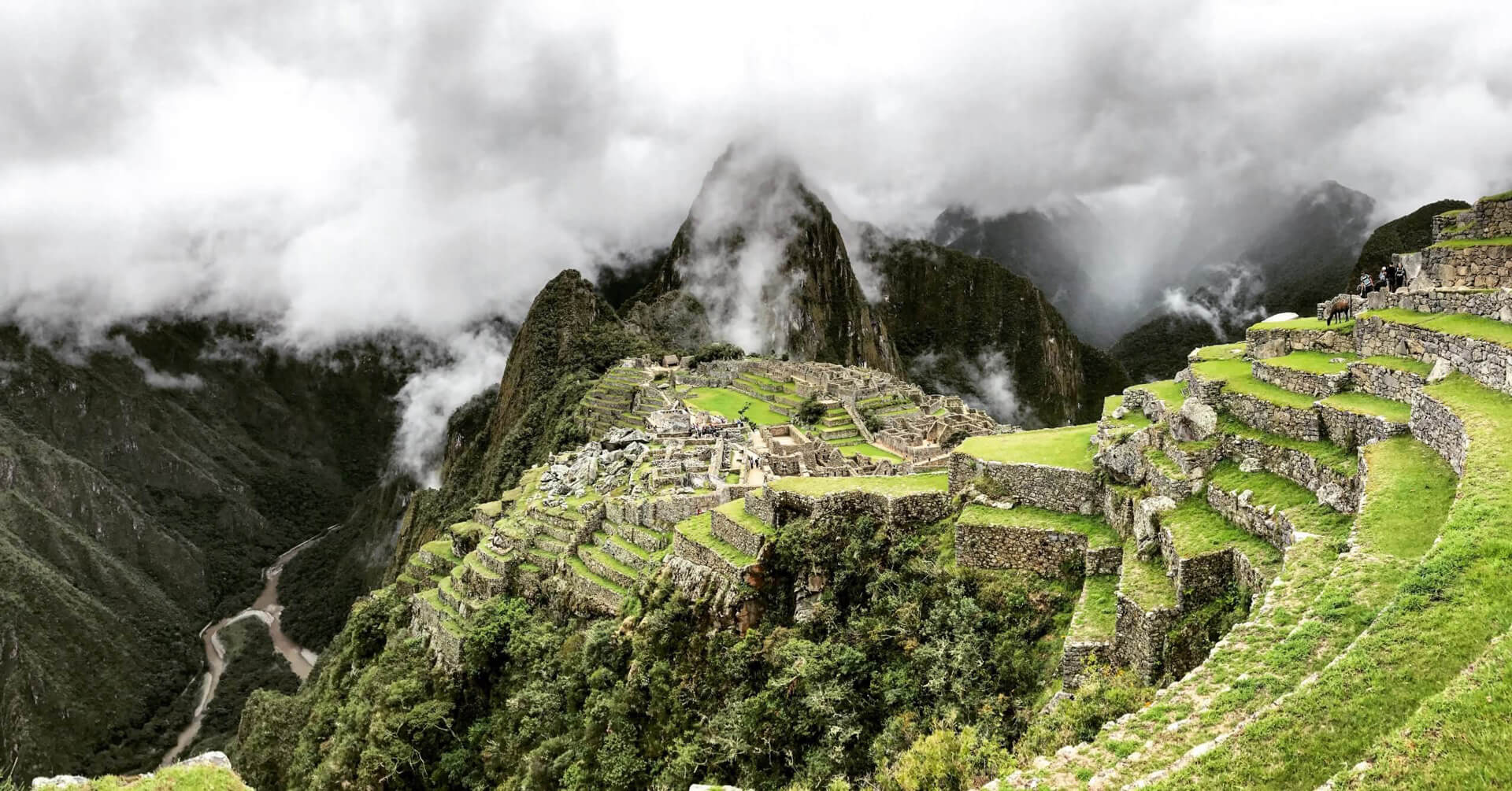 Ruins of Machu Picchu from one side of the ancient complex on a day with many low clouds