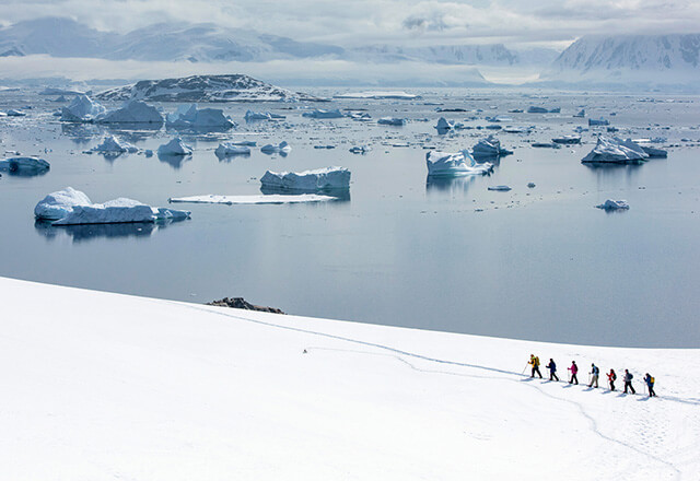 A small snowy wooden cabin surrounded by snow covered pine forest and mountains in Swedish Lapland