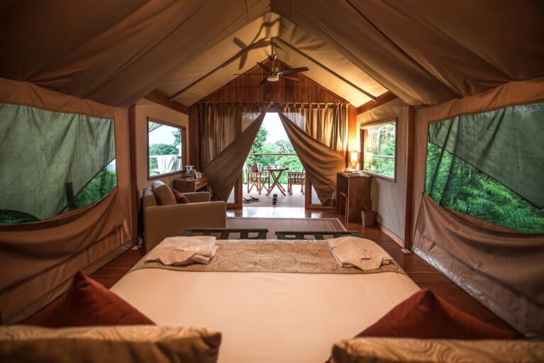 Luxury tented suite with bed, reading chairs, and balcony at Safari Camp in Galapagos Islands