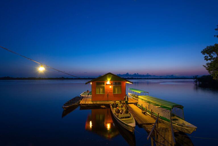 A family on a private boat tour of the Amazon by night leaving from the dock at Anavilhanas Jungle Lodge