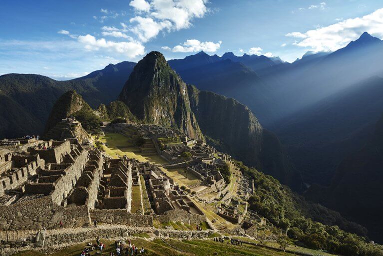 View of the ancient ruins of Machu Picchu and surrounding green mountains in the morning light