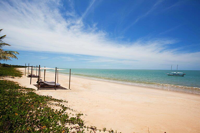 Beach with shaded lounge chairs and turquoise waters in Bahia during luxury Brazil tour