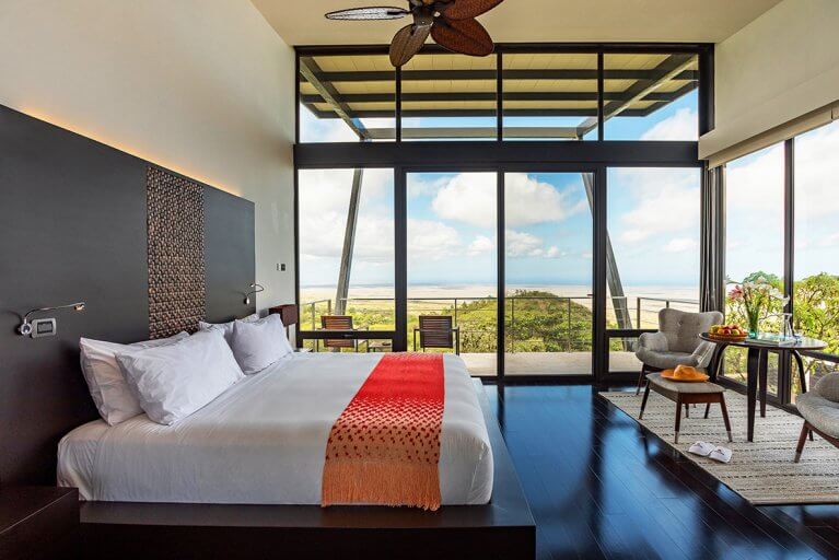 Spacious luxury suite with large bed, balcony, and island view at Pikaia Lodge in Galapagos Islands