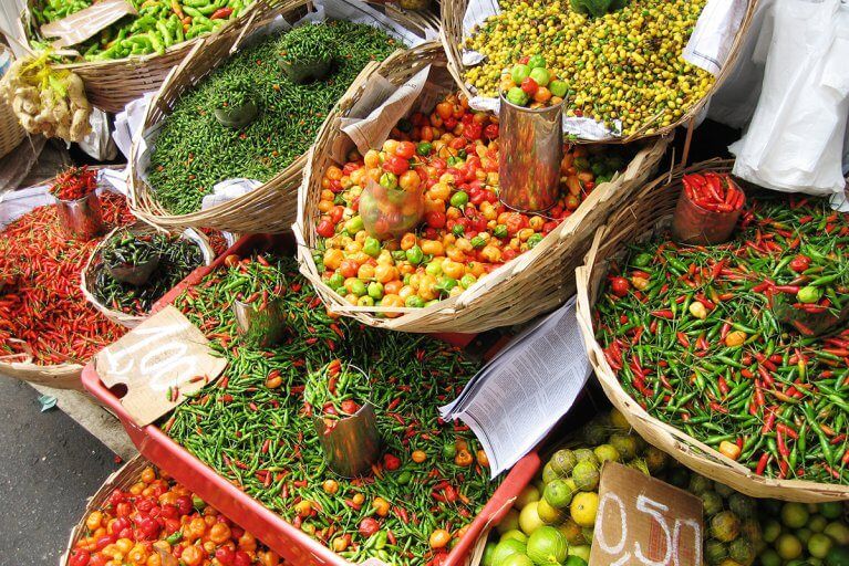 Baskets of different types of chili peppers for sale in a market during a private tour of Bahia