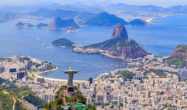 Looking down at back of Christ the Redeemer, buildings of Rio de Janeiro, mountains, and bay