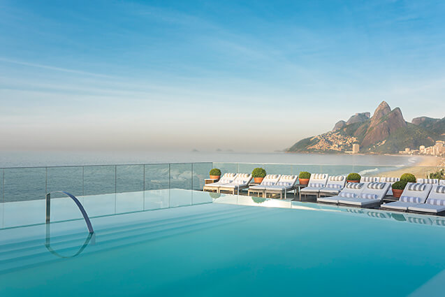 Outdoor pool and sun loungers at Hotel Fasano in Rio de Janeiro with beach and mountains in background on luxury Brazil trip