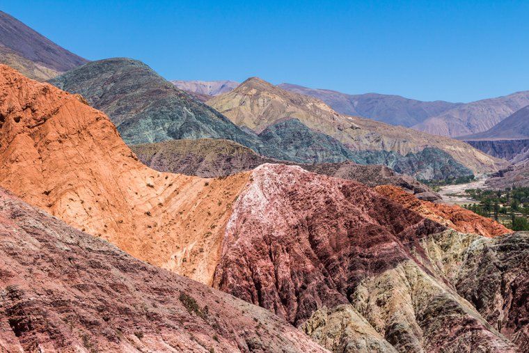 A colorful striped hill known as the Hill of Seven Colors against a blue sky near Purmamarca, Argentina