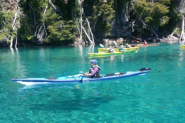 Woman enjoying a private kayaking tour on crystal clear waters in Argentina's Lake District