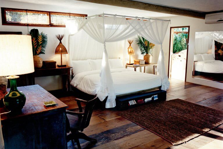 Spacious luxury suite with four-poster bed with white curtains at Uxua Hotel in Bahia, Brazil