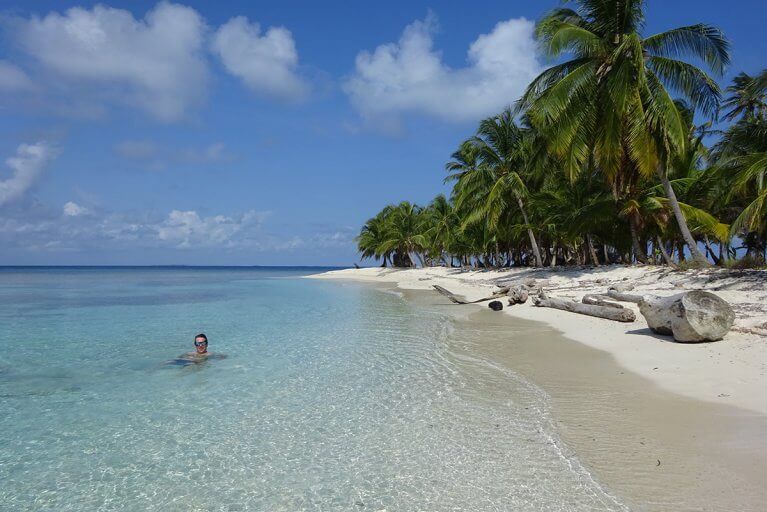 Swimming in crystal-clear waters near a white sand beach during a luxury tour of the San Blas Islands