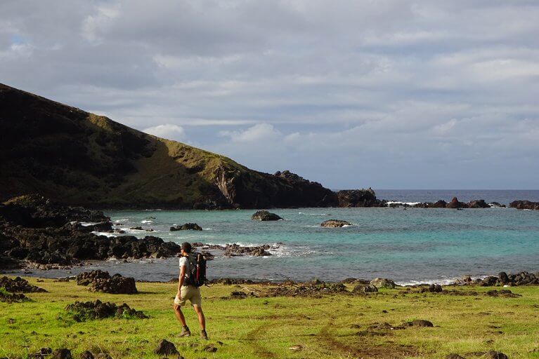 Man treks through the grass on Easter Island's coast during a private guided hike