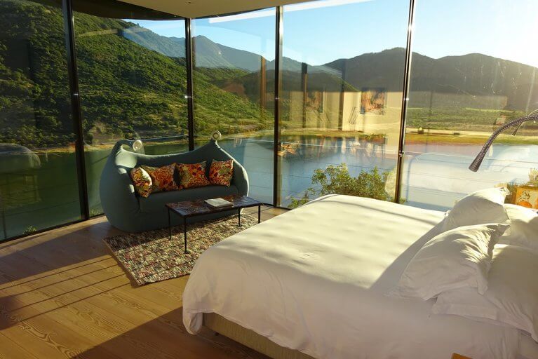 Master suite with floor-to-ceiling windows and lake and mountain views at luxury hotel Viña Vik Chile