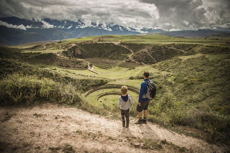 Father and son looking out towards the circular terraced depressions of the Moray ruins during a private hiking excursion