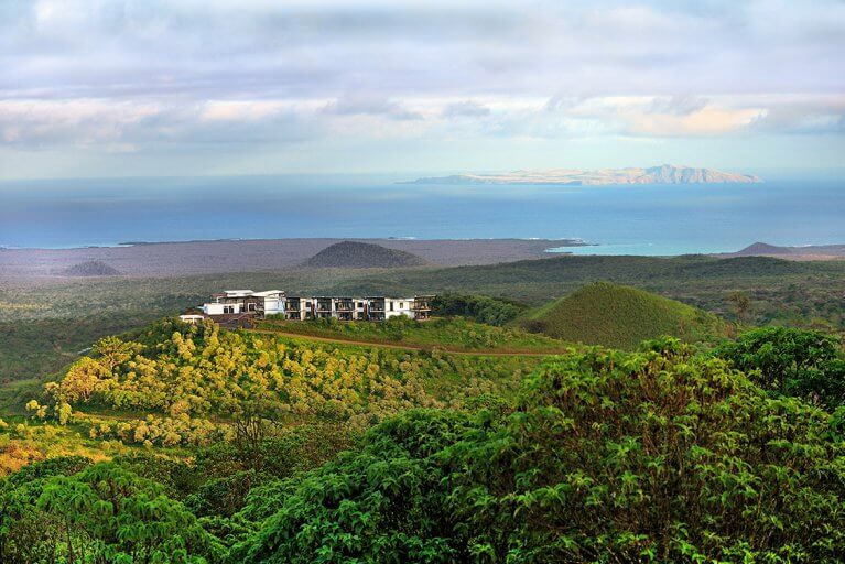 Luxury Pikaia Lodge from afar surrounded by nature with ocean in background in Galapagos Islands