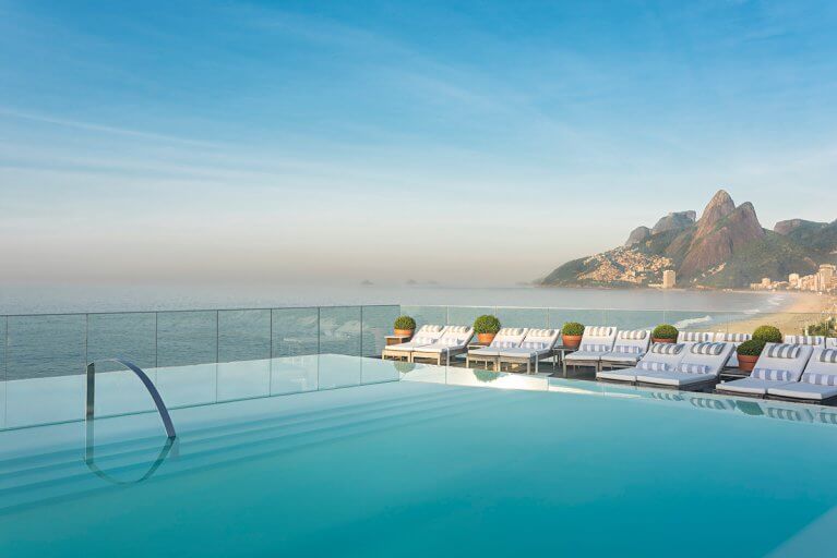 Outdoor pool and sun loungers at Hotel Fasano in Rio, with the beach and mountains in the background on a luxury Brazil trip