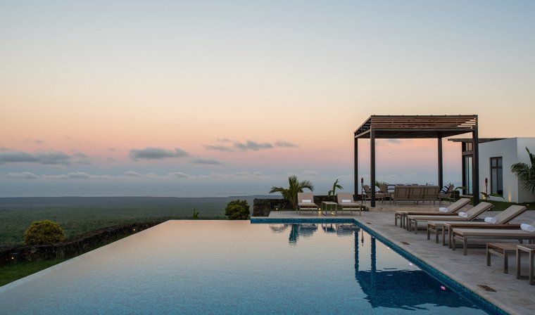 Infinity pool at Pikaia Lodge at sunset with sun loungers during luxury Galapagos Islands tour