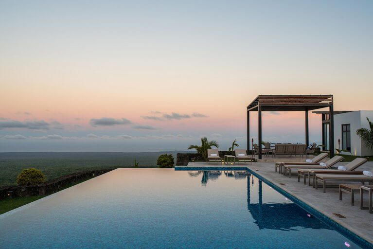 Infinity pool at Pikaia Lodge at sunset with sun loungers during luxury Galapagos Islands tour