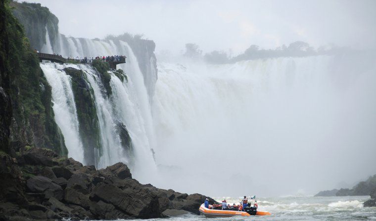People enjoying a private boat tour looking at the misty Iguazu Falls on an exclusive Brazil tour