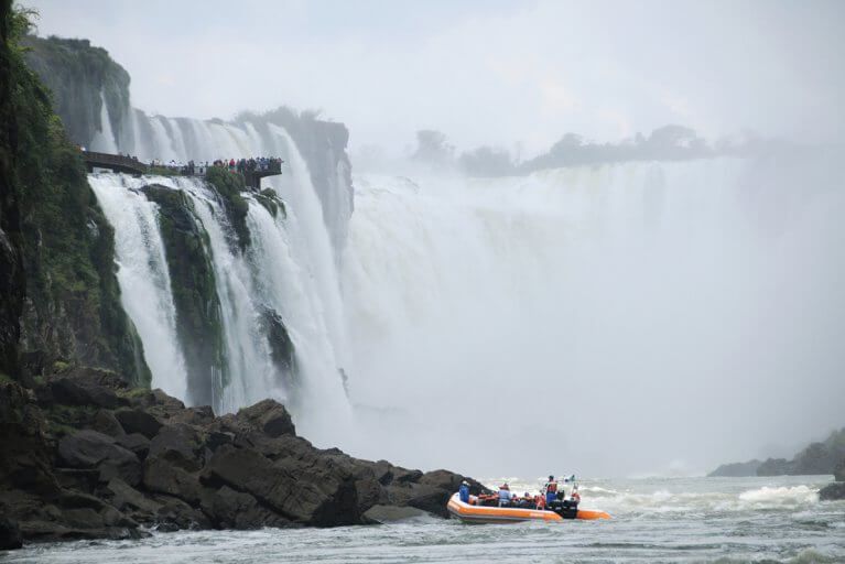 People enjoying a private boat tour looking at the misty Iguazu Falls on an exclusive Brazil tour