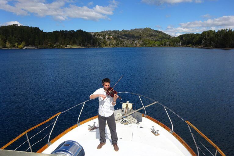 A musician gives a private violin concert on a boating excursion during a luxury tour of the Argentina's Lake District