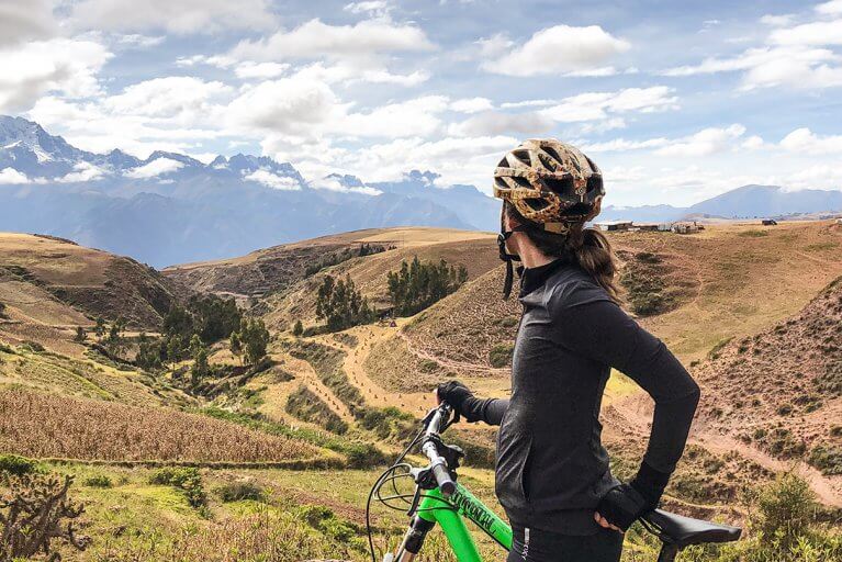 Woman in biking gear looking toward the Sacred Valley and mountains on a private bike tour