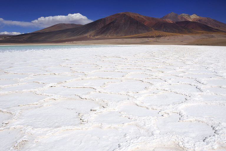 Brilliant white salt flats in front of mountains in the Atacama Desert during a luxury Chile tour