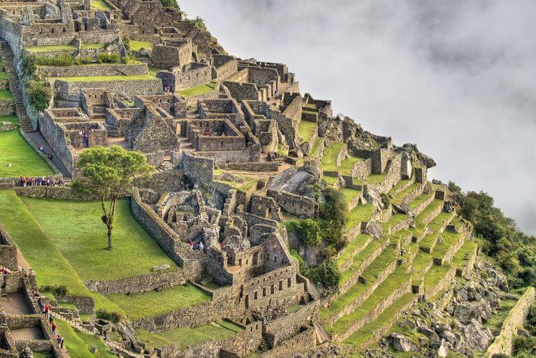 Side view looking down into ruins of Machu Picchu against a misty cloud