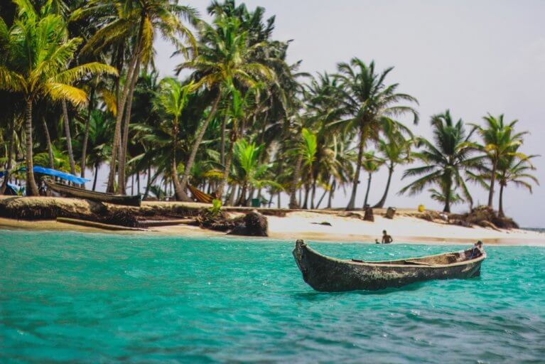 Small fishing boat floating next to private island in the San Blas Islands, Panama