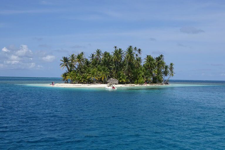 View of a small, uninhabited island lush with palm trees from the Caribbean Sea