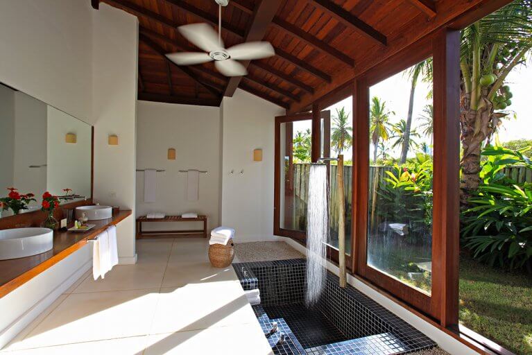Spacious bathroom with sunken shower and view of palm trees at Fazenda São Francisco Corumbau Hotel in Bahia, Brazil