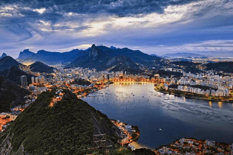 Looking down over Sugarloaf Mountain, bay, and Rio de Janeiro with city lights at sunset