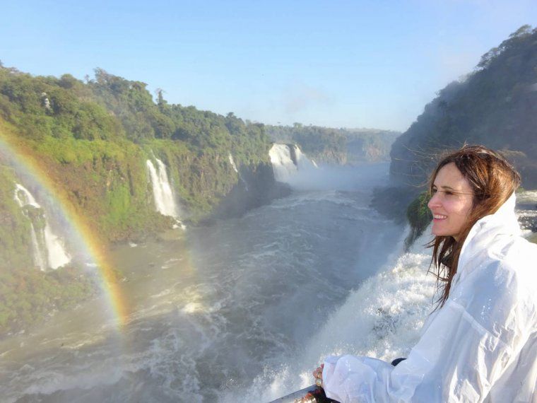Woman on a private tour looking out towards Iguazu Falls with a rainbow over the river