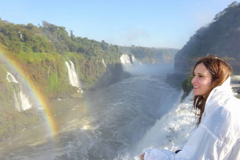 Woman on a private tour looking out towards Iguazu Falls with a rainbow over the river