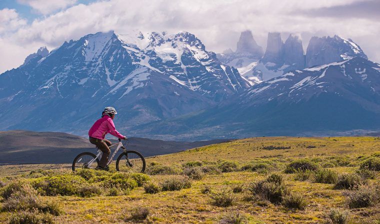 Girl biking in Patagonia with mountain backdrop during private Patagonia tour