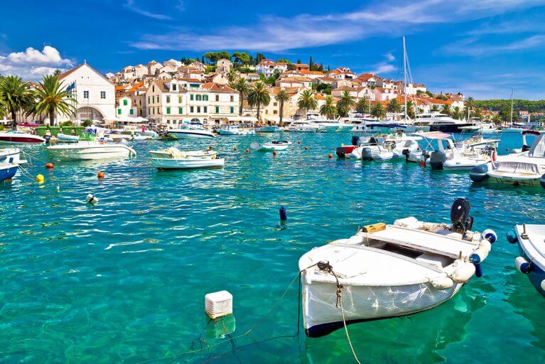 Boats anchored in Hvar harbour with white buildings on a hill in background