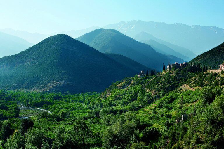 Landscape showing the green valleys of the Atlas Mountains with a kasbah in the distance