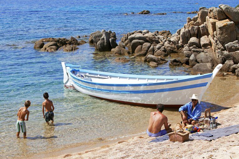 Family enjoying a gourmet picnic on beach during private boating excursion in Corsica