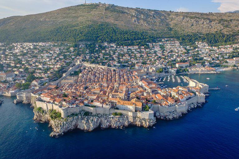 Aerial view of Dubrovnik's Old Town and Adriatic sea with surrounding houses and hillside in background