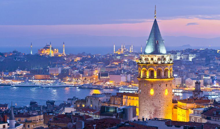Galata Tower lit up at night with view of Bosphorus River and European side of Istanbul
