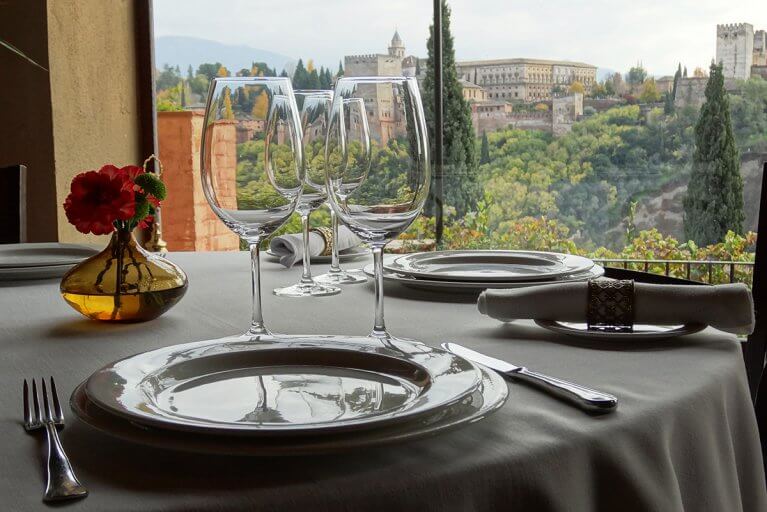Plates set for a gourmet meal at Restaurante Juan Ranas with view of Alhambra in Spain