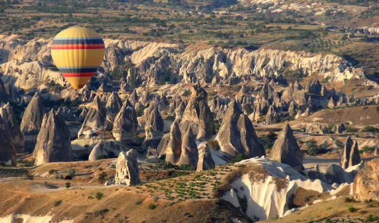 Hot air balloon floats over fairy towers in Cappadocia