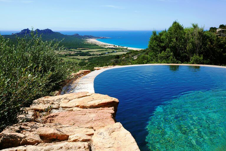 Outdoor pool with a view of fields, mountains, and coast at Domaine de Murtoli in Corsica
