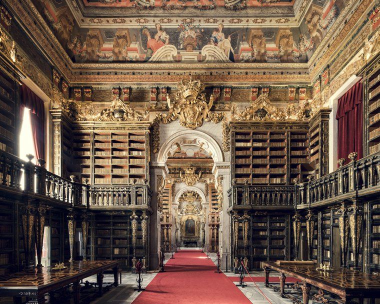 Ornate interior with tall bookshelves at the Joanina Library in Coimbra, Portugal