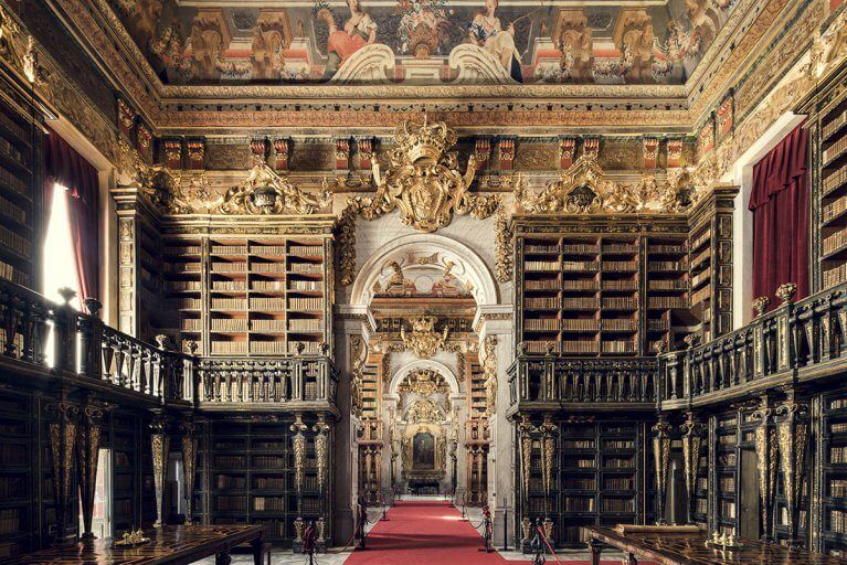 Ornate interior with tall bookshelves at the Joanina Library in Coimbra, Portugal
