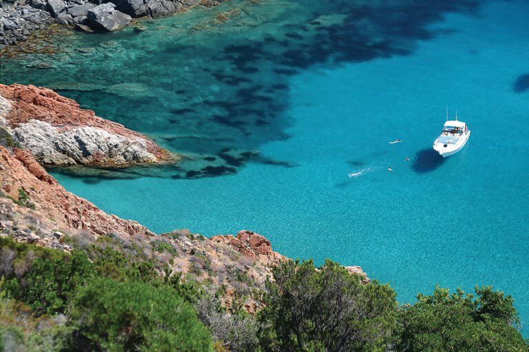Aerial view of privately chartered yacht in blue sea off rocky coast of Corsica