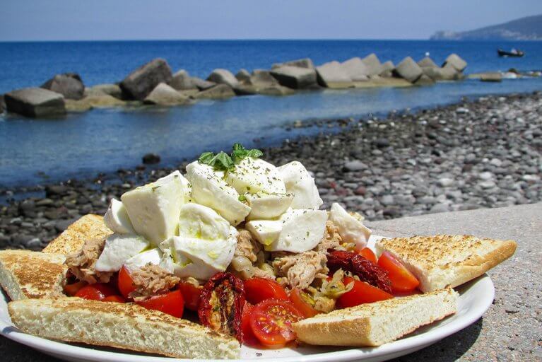 Close up of traditional Pane Cunzato lunch by the sea in Sicily