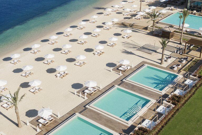 Aerial view of private beach, pools, and sun loungers with umbrellas at One&Only luxury resort in Montenegro