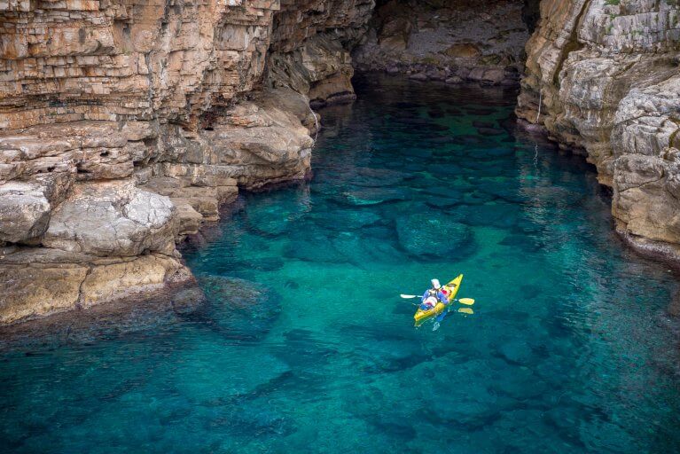 Aerial view of man sea kayaking in cave of Lokrum islands near Dubrovnik