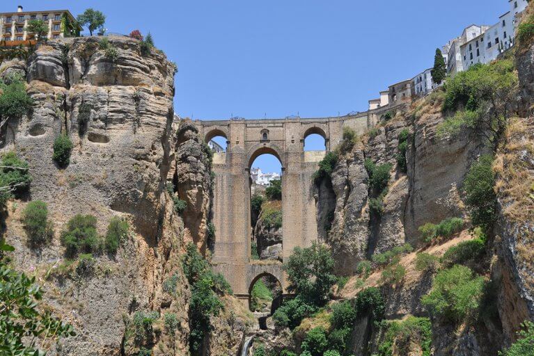 Stone New Bridge with tall arches between rocky cliffs in Ronda, Spain